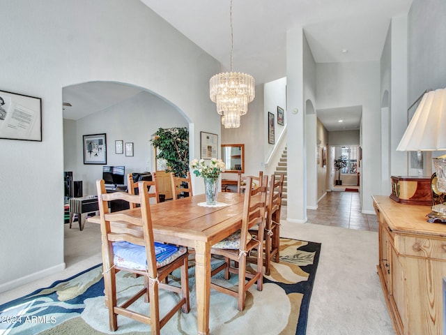 dining space featuring high vaulted ceiling, a chandelier, and light colored carpet