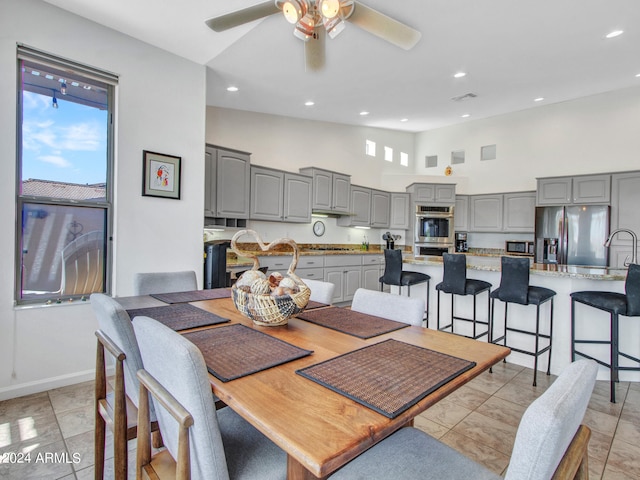 dining area featuring ceiling fan, light tile patterned floors, and high vaulted ceiling