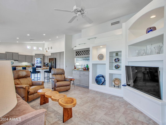 living room featuring built in shelves, ceiling fan, and high vaulted ceiling