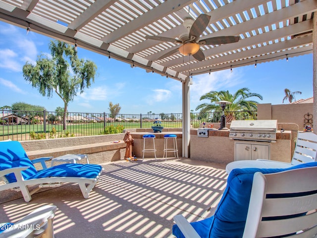 view of patio with ceiling fan, grilling area, an outdoor kitchen, and a pergola