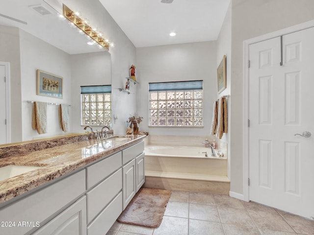 bathroom with a wealth of natural light, tile patterned floors, a relaxing tiled tub, and vanity