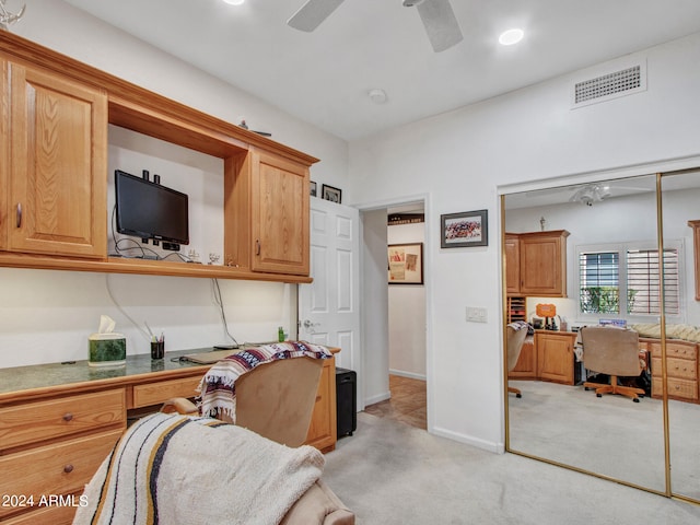 interior space featuring built in desk, ceiling fan, and light colored carpet