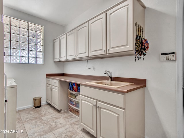 kitchen featuring sink, washer / dryer, and white cabinets