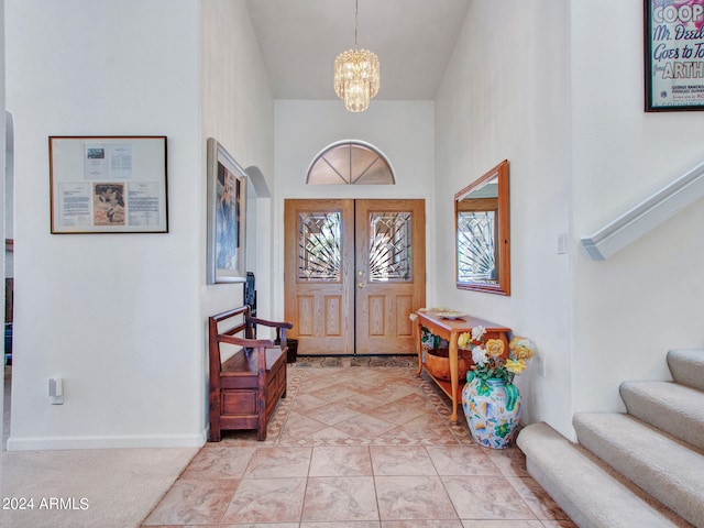 entryway featuring a notable chandelier, a towering ceiling, and light tile patterned floors