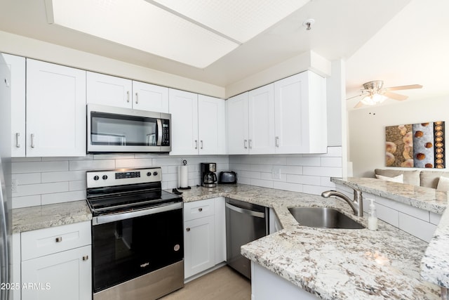 kitchen featuring stainless steel appliances, a sink, decorative backsplash, and white cabinetry