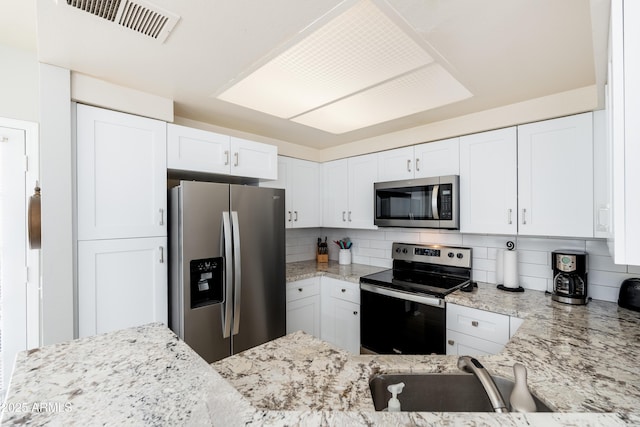kitchen featuring stainless steel appliances, decorative backsplash, and light stone countertops