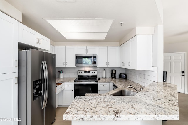 kitchen featuring appliances with stainless steel finishes, a sink, a peninsula, and tasteful backsplash