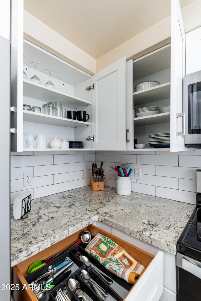 kitchen featuring backsplash, appliances with stainless steel finishes, open shelves, and white cabinets