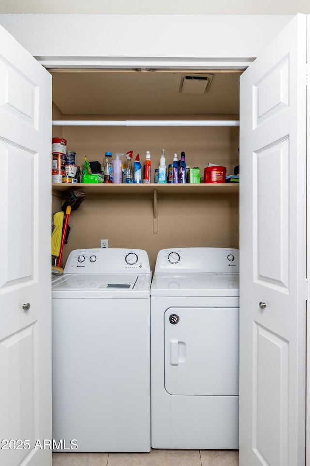 laundry area with independent washer and dryer and light tile patterned floors