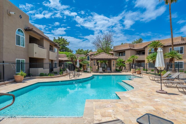 community pool with fence, a patio area, a residential view, and a gazebo