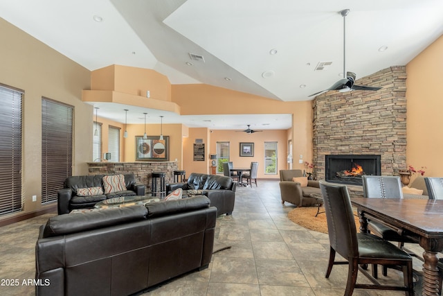 living area with a stone fireplace, ceiling fan, and high vaulted ceiling