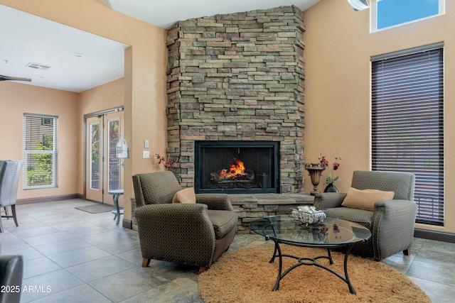 tiled living area with a stone fireplace and baseboards