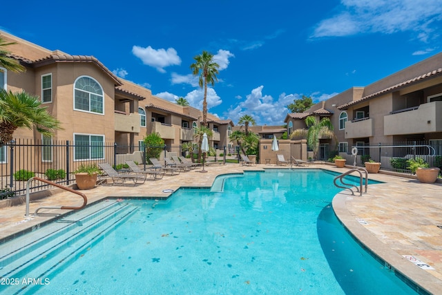 community pool featuring a residential view, fence, and a patio area