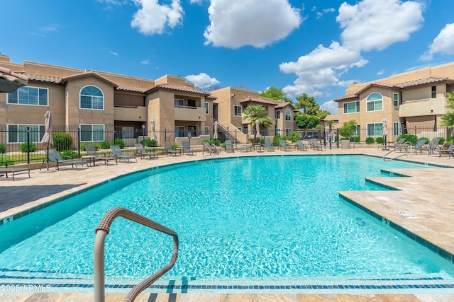 community pool featuring fence, a residential view, and a patio