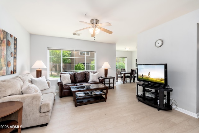 living area with plenty of natural light, ceiling fan, light wood-type flooring, and baseboards