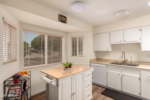 kitchen with light countertops, white cabinets, white dishwasher, a sink, and wood finished floors