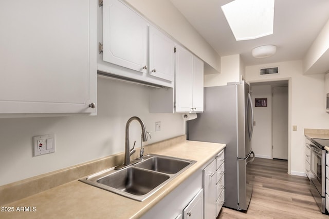 kitchen featuring white cabinetry, light wood-style floors, visible vents, stainless steel appliances, and a sink