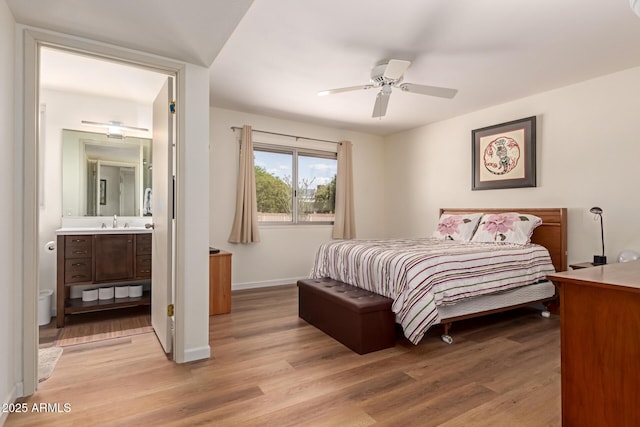 bedroom with ceiling fan, connected bathroom, light wood-style flooring, a sink, and baseboards