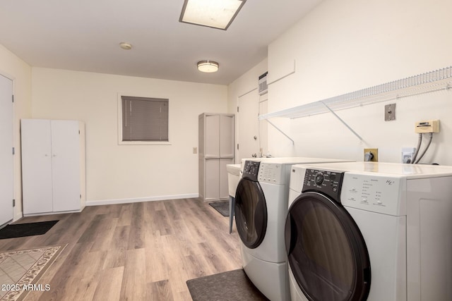 washroom featuring light wood-style flooring, independent washer and dryer, laundry area, and baseboards