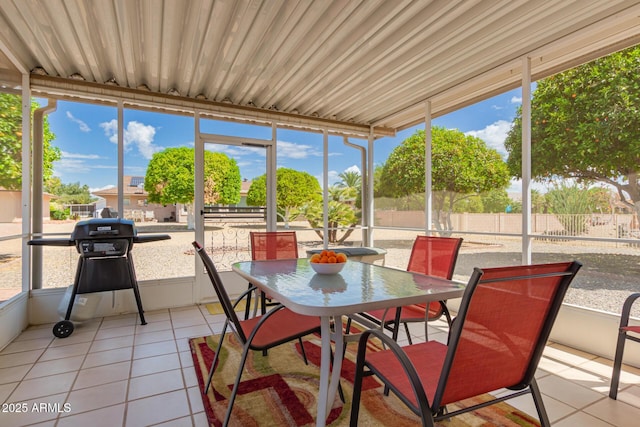 sunroom / solarium with a wealth of natural light, tile patterned flooring, and outdoor dining area