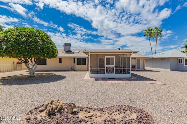 rear view of property with fence and a sunroom