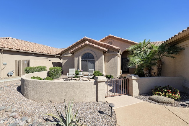 9216 E Rocky Lake Dr, Sun Lakes, AZ 85248 - mediterranean / spanish-style house with a gate, a tile roof, stucco siding, and a fenced front yard
