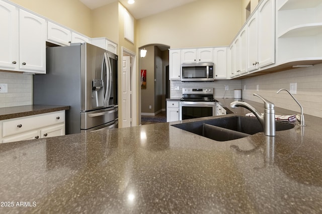 9216 E Rocky Lake Dr, Sun Lakes, AZ 85248 - kitchen with a sink, decorative backsplash, arched walkways, white cabinets, and appliances with stainless steel finishes