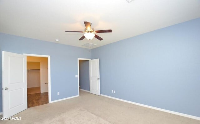 unfurnished bedroom with ceiling fan, light colored carpet, a spacious closet, and a closet