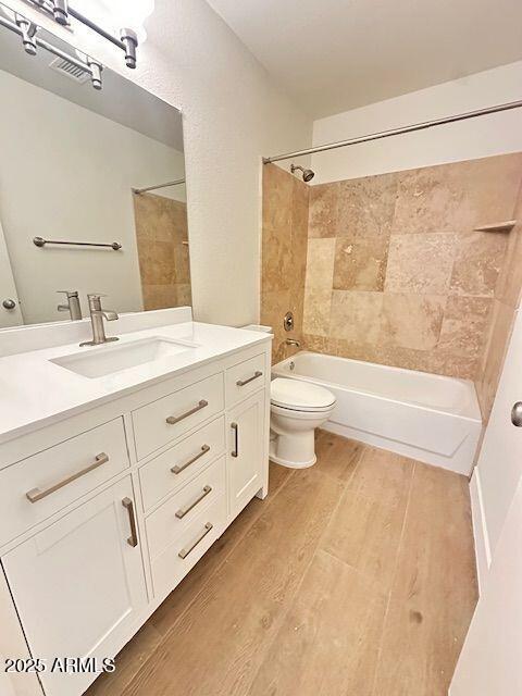 full bathroom with wood-type flooring, toilet, vanity, and tiled shower / bath