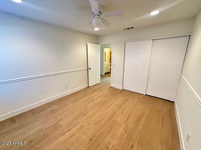 unfurnished bedroom featuring ceiling fan, light hardwood / wood-style floors, and a closet