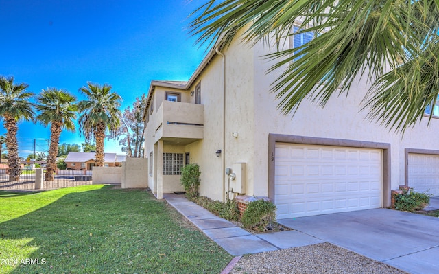 view of property exterior featuring stucco siding, a yard, concrete driveway, and fence