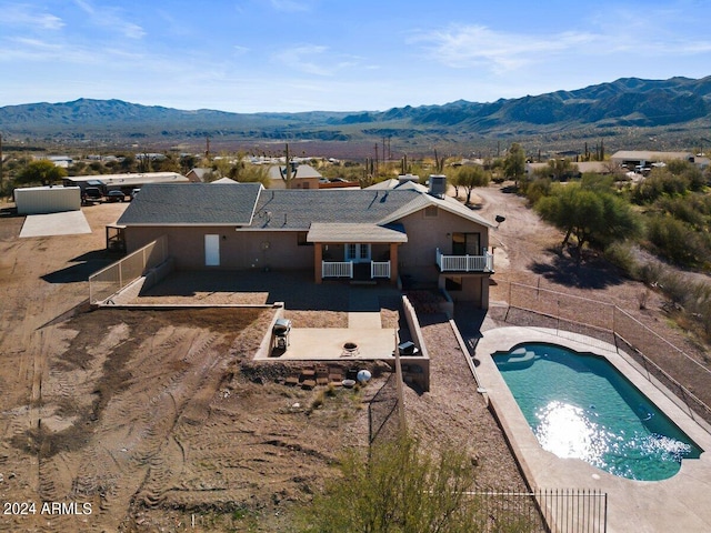 exterior space featuring a mountain view, a patio area, a fenced in pool, and a balcony