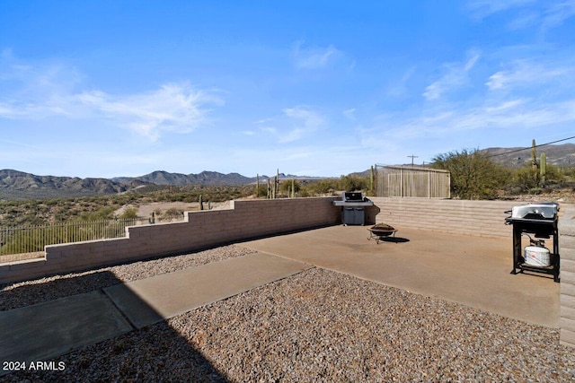 view of patio with a fire pit, a mountain view, and grilling area