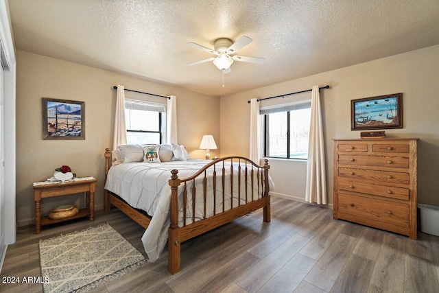 bedroom featuring a textured ceiling, multiple windows, ceiling fan, and dark hardwood / wood-style floors