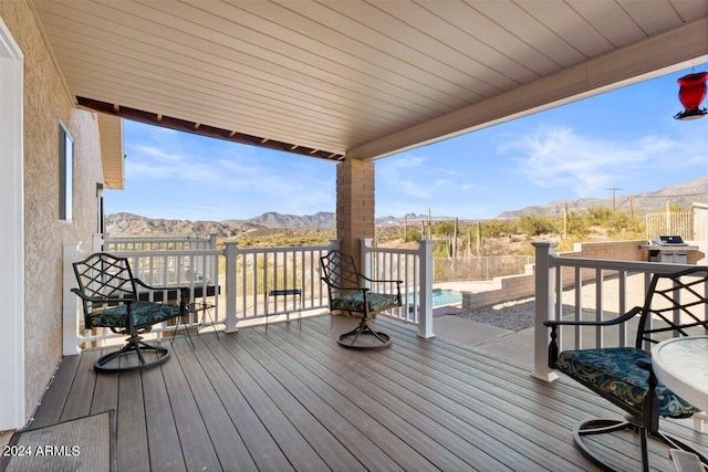 wooden deck with a mountain view and a patio area