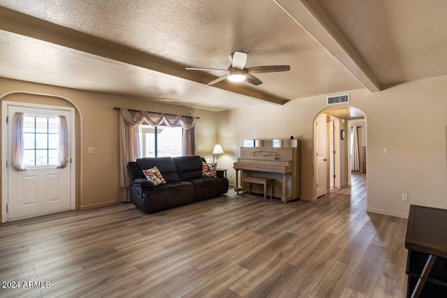 living room featuring beamed ceiling, hardwood / wood-style floors, a textured ceiling, and plenty of natural light