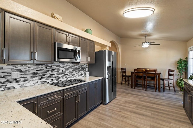 kitchen with light stone countertops, dark brown cabinetry, stainless steel appliances, ceiling fan, and light hardwood / wood-style flooring