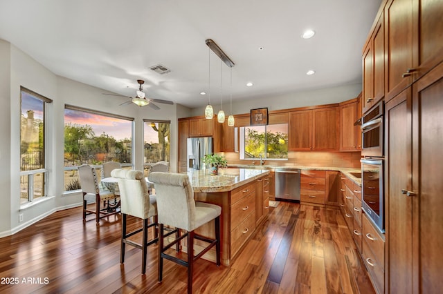 7304 E Bent Tree Dr, Scottsdale, AZ 85266 - kitchen featuring stainless steel appliances, brown cabinets, dark wood finished floors, a breakfast bar, and recessed lighting