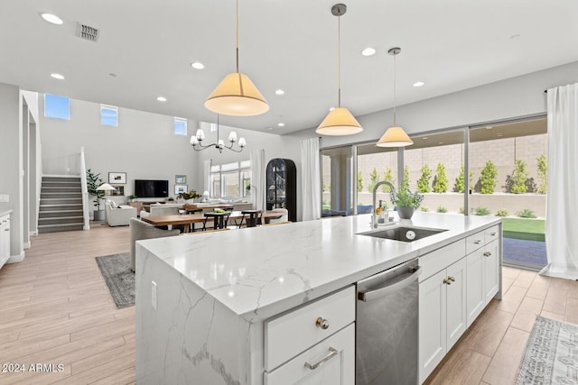 kitchen featuring an island with sink, dishwasher, pendant lighting, white cabinets, and sink