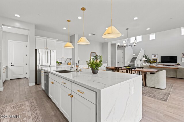 kitchen with sink, white cabinetry, an island with sink, and hanging light fixtures