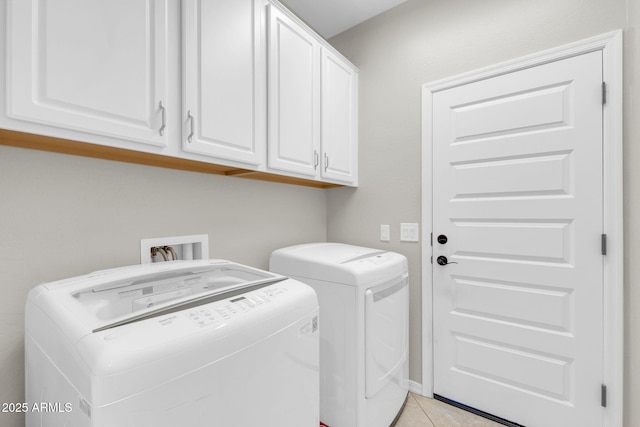 washroom featuring washer and dryer, cabinets, and light tile patterned flooring