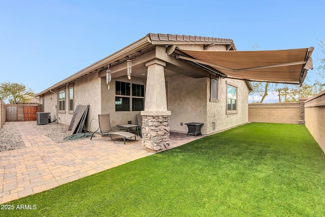 rear view of house with cooling unit, a yard, and a patio area