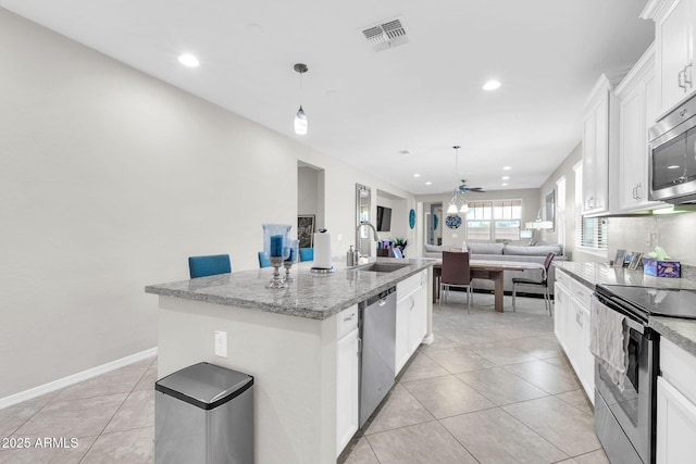 kitchen featuring sink, an island with sink, pendant lighting, stainless steel appliances, and white cabinets