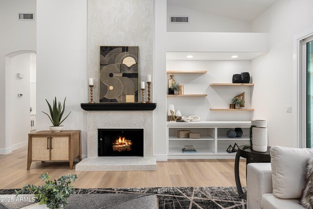 8965 E Maple Dr, Scottsdale, AZ 85255 - living room featuring a premium fireplace, wood finished floors, arched walkways, and vaulted ceiling