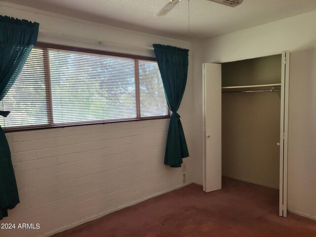 unfurnished bedroom with a textured ceiling, carpet flooring, ceiling fan, and a closet