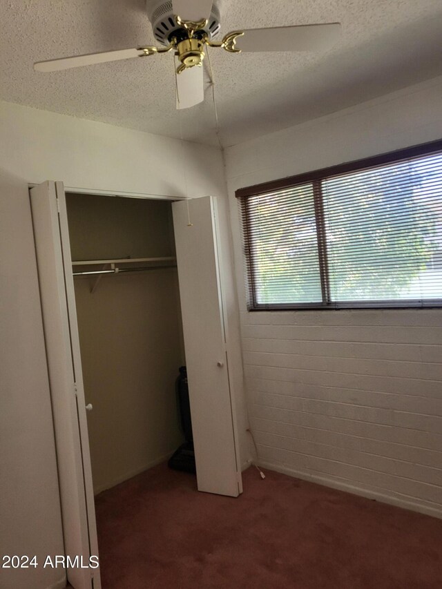 unfurnished bedroom with a closet, ceiling fan, carpet floors, and a textured ceiling