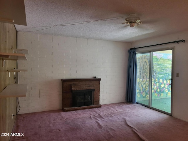 unfurnished living room with a textured ceiling, plenty of natural light, a brick fireplace, and carpet