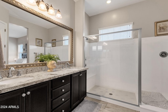 bathroom with a shower with door, vanity, and tile patterned floors