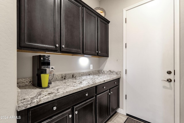 kitchen featuring dark brown cabinets and light stone countertops