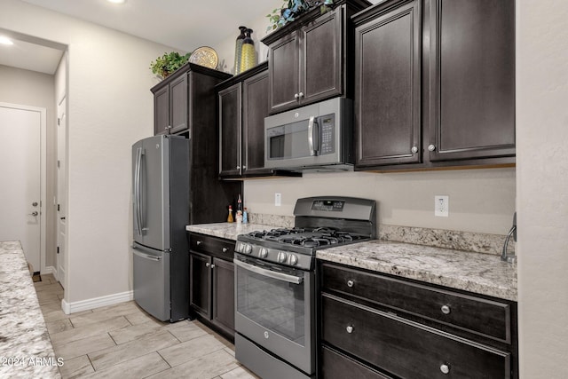 kitchen featuring light stone counters, appliances with stainless steel finishes, and dark brown cabinets